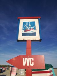 Low angle view of road sign against blue sky