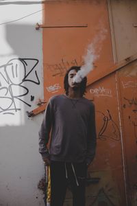 Man standing by graffiti on wall