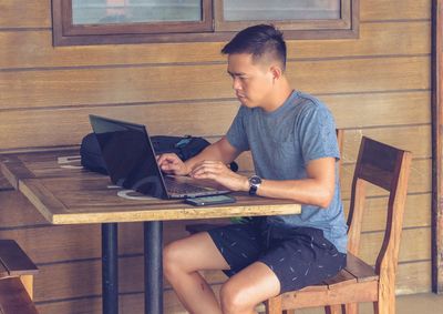 Boy using mobile phone while sitting on table