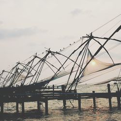 Commercial fishing nets at sea against sky during sunset