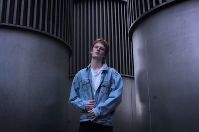 Low angle portrait of young man standing by built structures