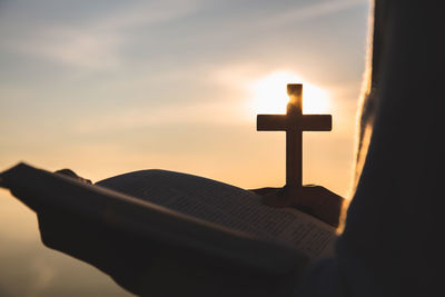 Cross in cemetery against sky during sunset