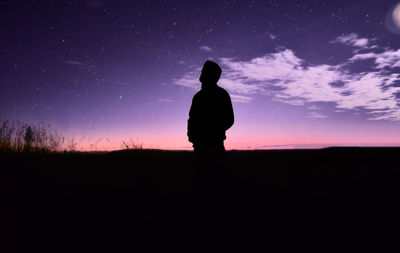 Silhouette woman standing on field against sky during sunset