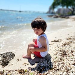 Side view of boy sitting at beach