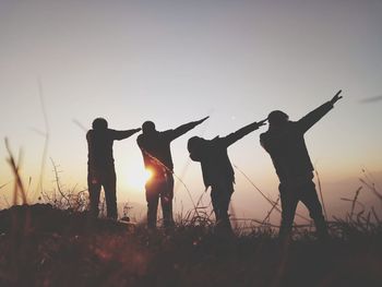 Silhouette people standing on field against sky during sunset