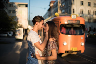 Romantic couple looking at each other while standing on road in city