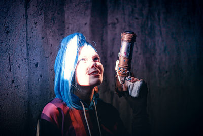 Portrait of young woman standing against wall