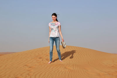 Full length of woman on sand at beach against clear sky