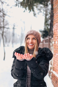 Portrait of smiling young woman standing outdoors during winter