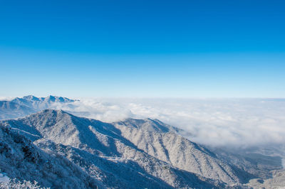 Scenic view of snowcapped mountains against blue sky