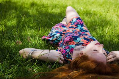 Young woman lying on grass field