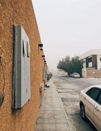 Car on street by buildings against clear sky