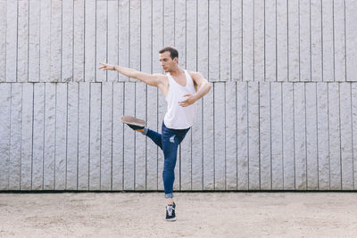 Full length of man jumping while dancing against wall