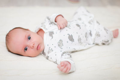 Portrait of cute baby lying on bed at home