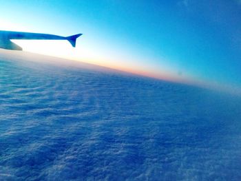 Airplane flying over sea against blue sky