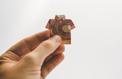 Close-up of hand holding origami against white background