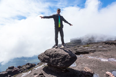 Man standing on rock against sky