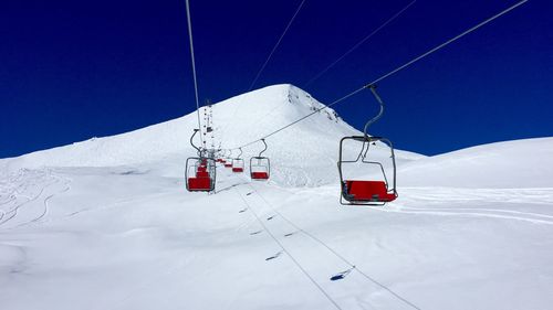 Ski lift on snow covered mountain against sky