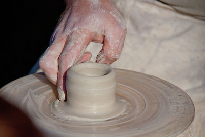 Cropped image of craftsperson shaping clay on pottery wheel