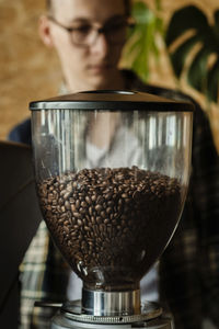 Coffee beans in an electric commercial coffee grinder in a cafe - professional barista. 