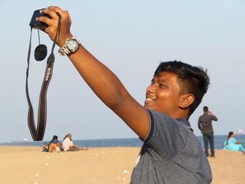 Friends on beach against clear sky