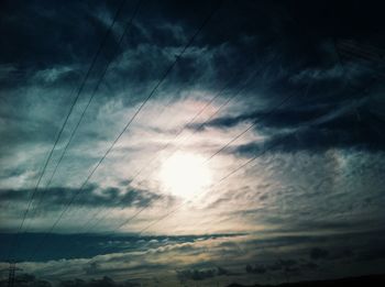 Low angle view of power lines against cloudy sky