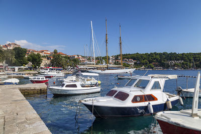 Sailboats moored on harbor against clear blue sky