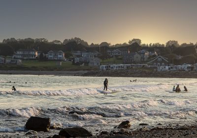 People on beach by sea against sky during sunset