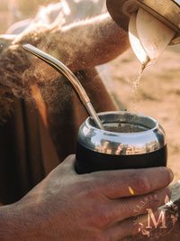 Close-up of hand pouring drink in water