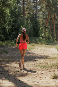 Full length of young woman standing at forest