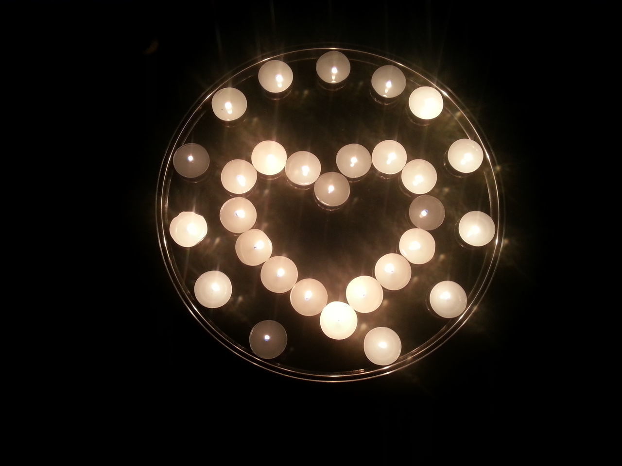 CLOSE-UP OF ILLUMINATED LIGHTS AGAINST BLACK BACKGROUND