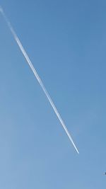 Low angle view of vapor trails in blue sky