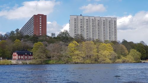 Scenic view of river by buildings against sky