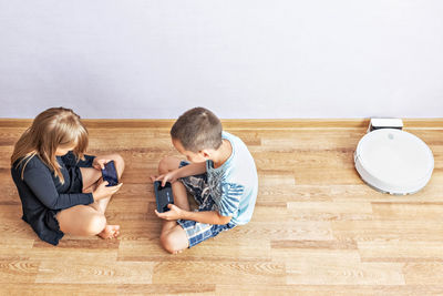 A boy and a girl-toddlers are sitting on the floor, opposite each other. 