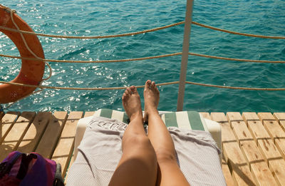 Low section of woman sunbathing on pier over sea