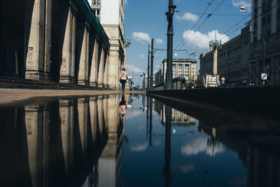 Reflection of man standing on water in city