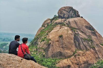 Rear view of people looking at mountain against sky