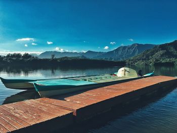 Boats moored on lake against blue sky