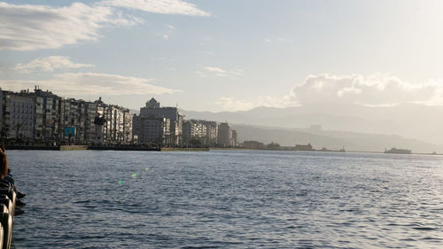 Sea by buildings against sky in city