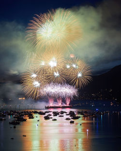 Firework display over river against sky