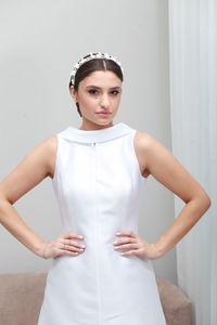 Indoor cropped  image of bride in white classic dress and bridal tiara, minimalist home interior