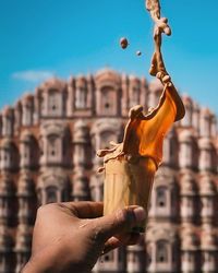 Midsection of man holding ice cream against building