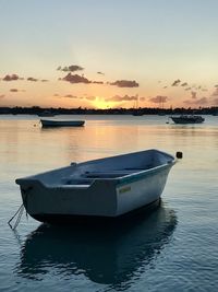 Boat in sea against sky during sunset