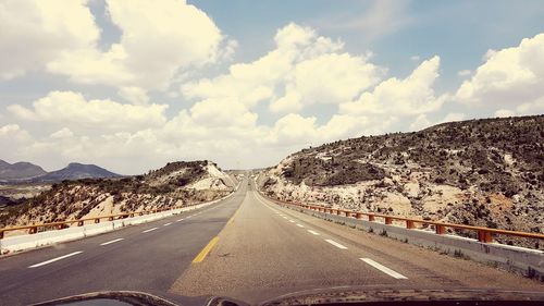 Empty road along landscape against sky