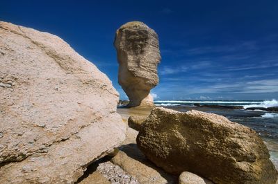 Statue on rock at beach against sky