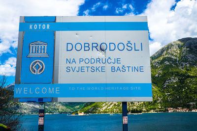 Low angle view of signboard against cloudy sky
