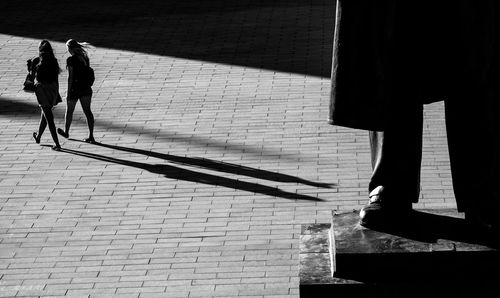 Woman walking on street against statue