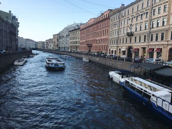 Boats moored in canal amidst buildings in city