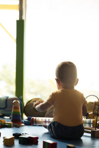 Rear view of boy sitting at table