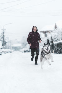 Full length of a dog on snow covered field